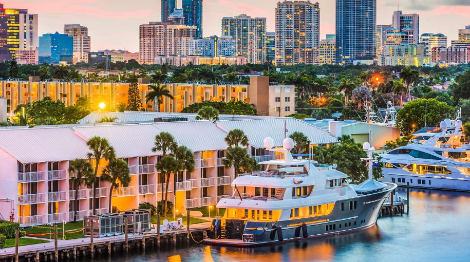 Yachts docked along the New River at sunset with the Fort Lauderdale skyline behind